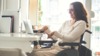 Fotografía: Mujer con discapacidad sonríe frente al computador.