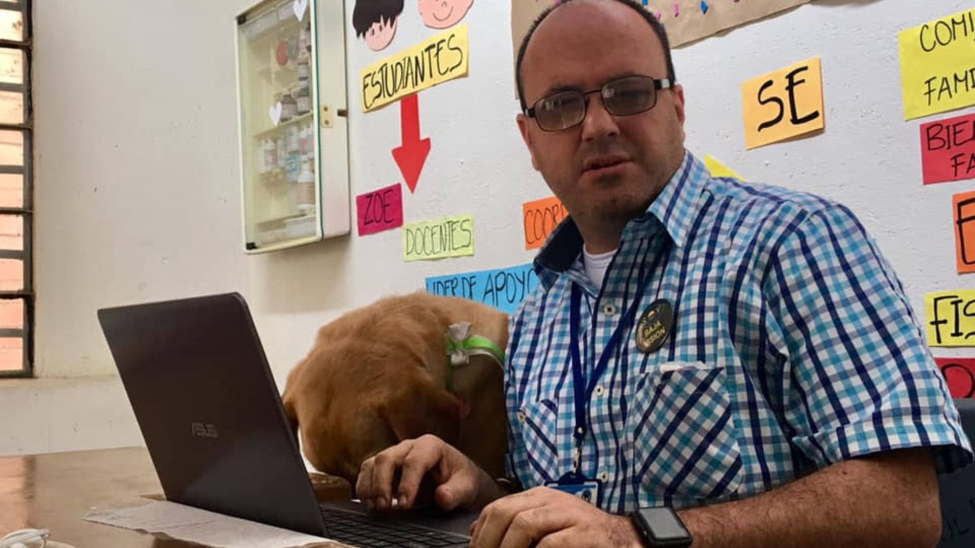 En la fotografía: Hernán Villegas frente a un computador portátil acompañado por su perro lazarillo.