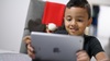 Fotografía: Niño interactúa con una tablet que tiene en sus manos.